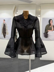Black lace blouse on a mannequin in a display setting with blurred background