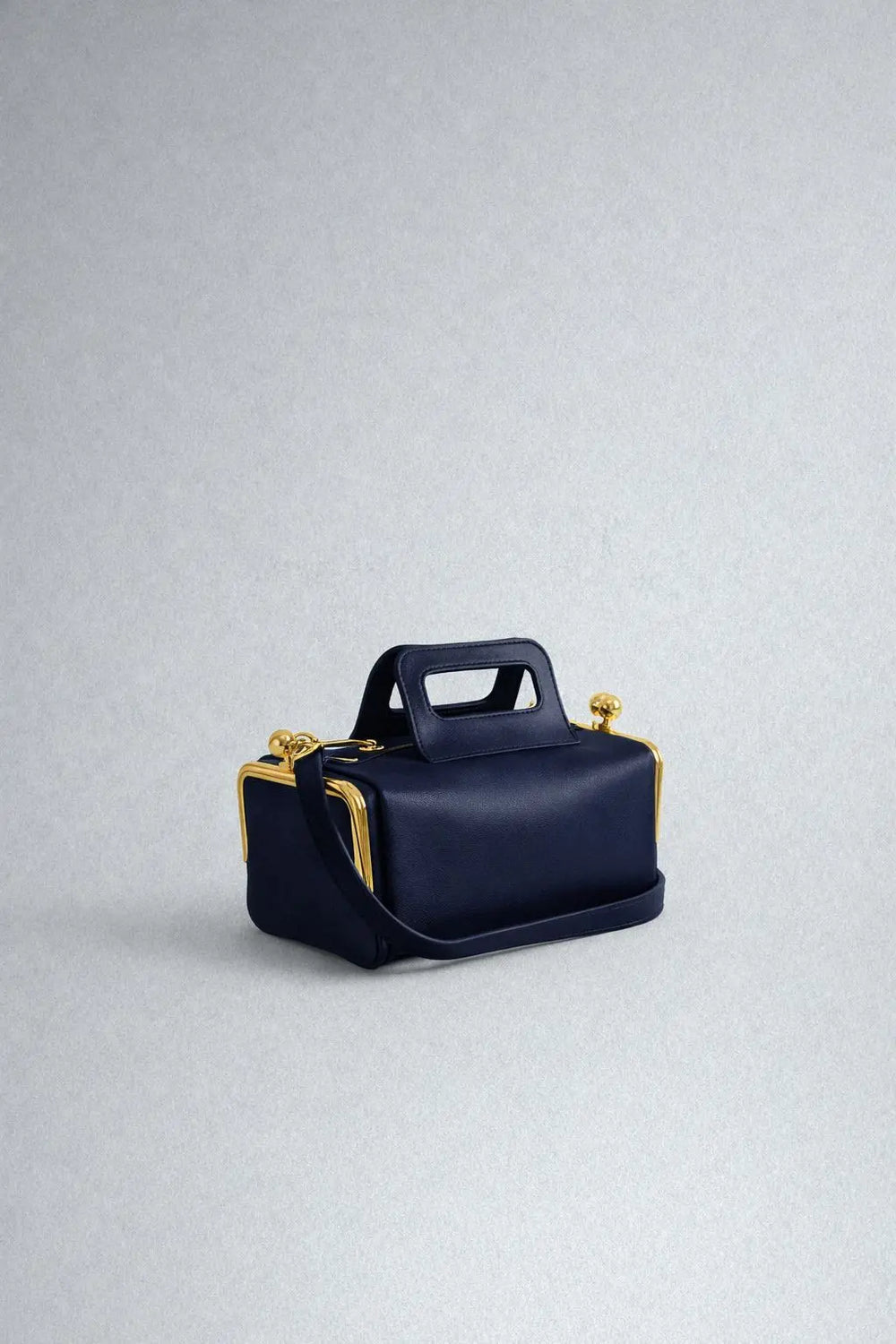 Navy blue handbag with gold accents on a light gray background