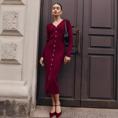 Woman in a burgundy dress standing in front of a large door.