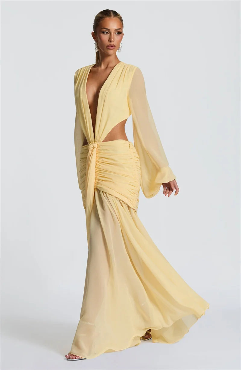 Woman wearing a yellow evening gown with a plunging neckline and long sleeves on a white background