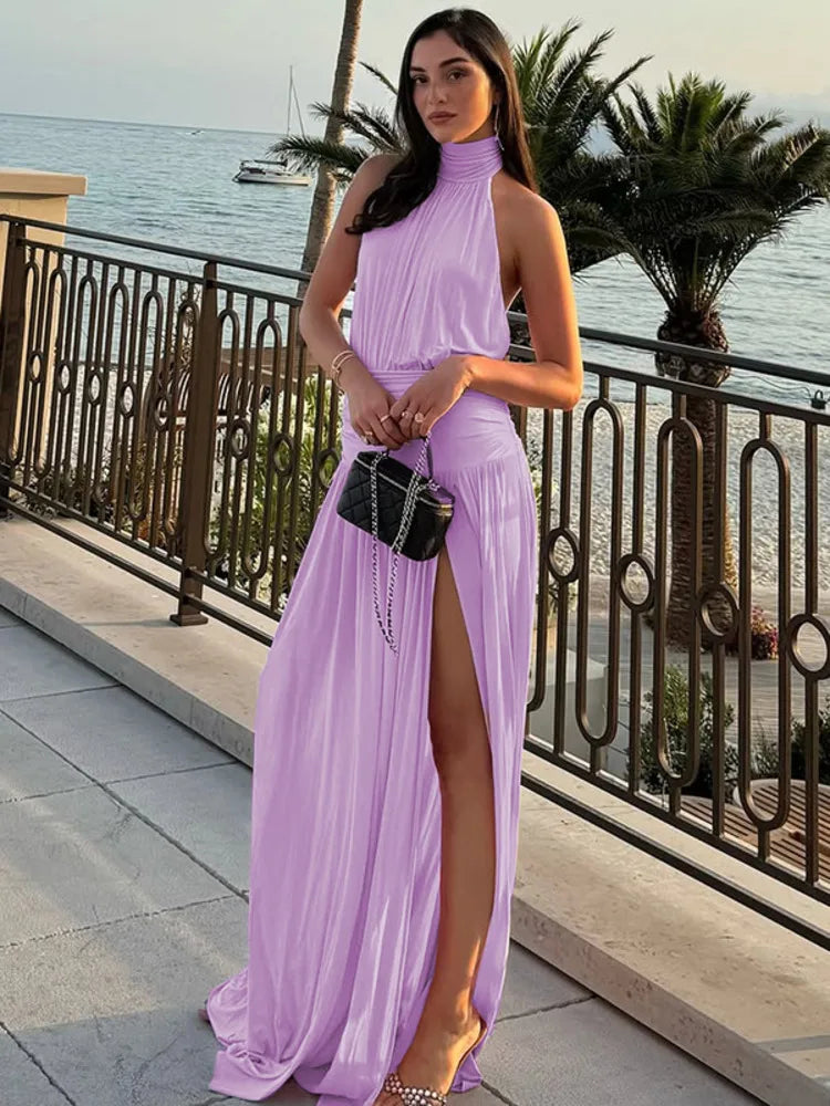 Woman in a lavender dress standing by a waterfront with palm trees in the background
