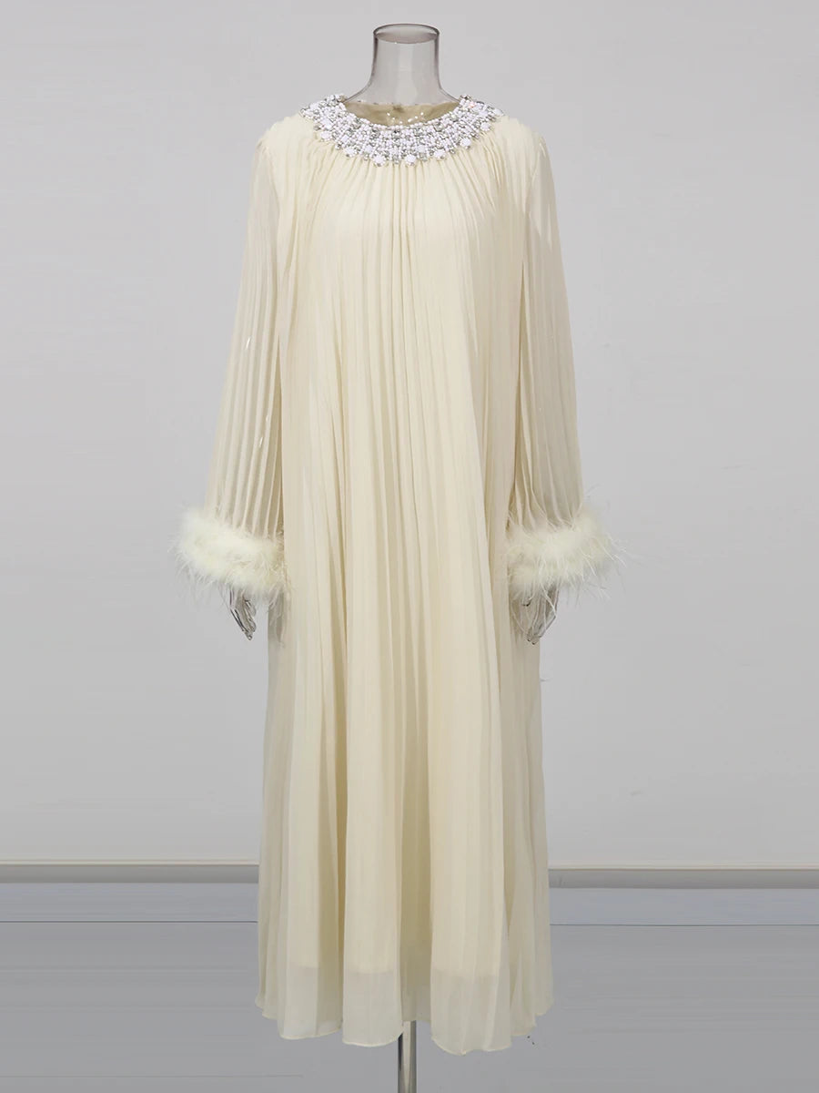 Cream-colored dress with feathered cuffs on a mannequin against a gray background