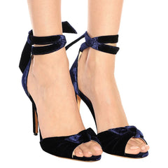 Model wearing blue velvet bow tie ankle strap high heel sandals