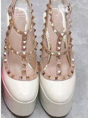 Pair of high-heeled sandals with gold studs on a light gray background