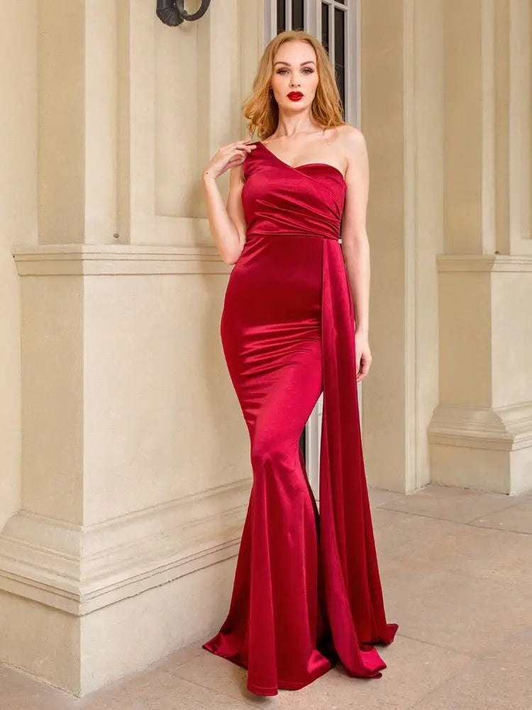 Golden Atelier maxi dress in satin with a one-shoulder design, padded shoulder detail, and a flowing skirt. Burgandy