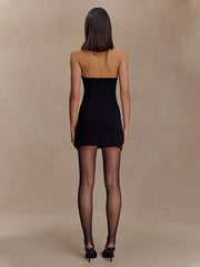 Woman wearing a black strapless dress against a beige background