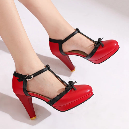 Red T-strap platform block heel pump with black trim and bow detail on a model's foot