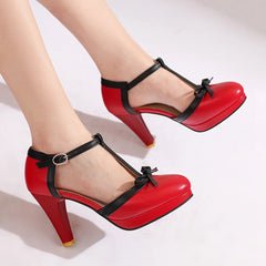 Red T-strap platform block heel pump with black trim and bow detail on a model's foot