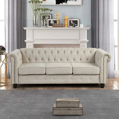 Beige tufted sofa in a living room setting with a fireplace and decorative items.