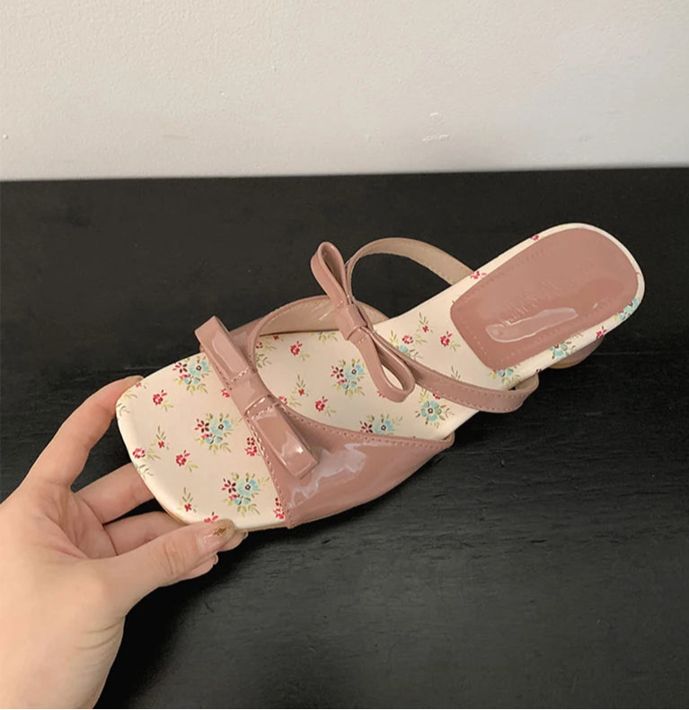 Pink sandal with floral pattern on a dark surface