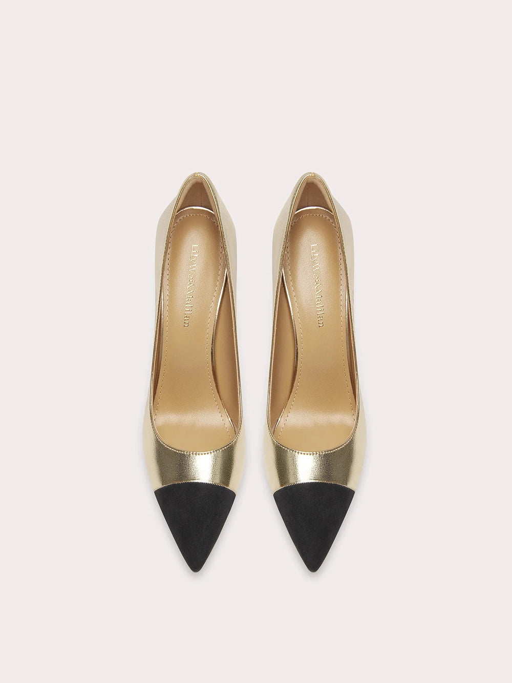 Pair of high-heeled shoes with gold bodies and black pointed toes on a light gray background