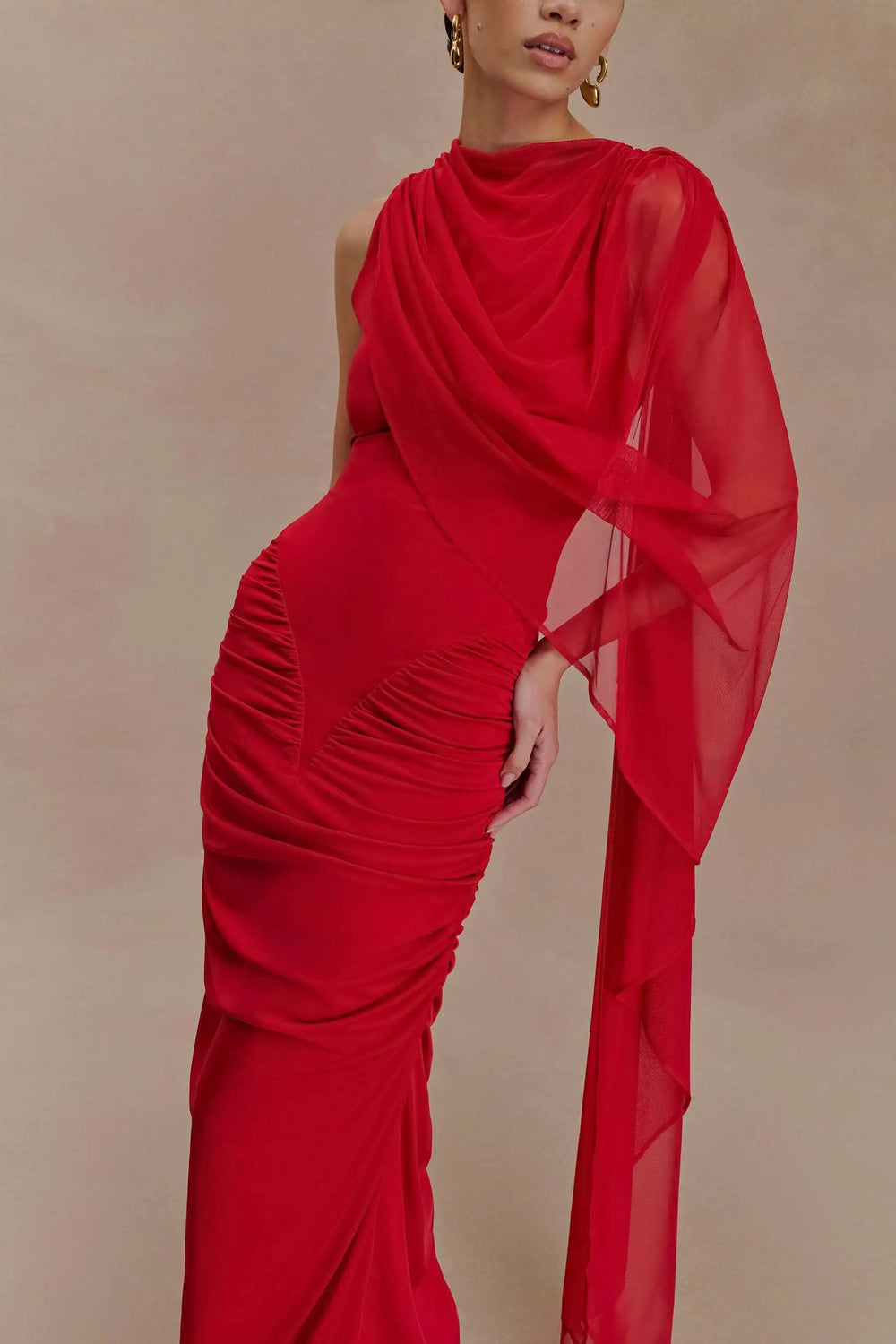 Red evening gown with sheer sleeves on a beige background