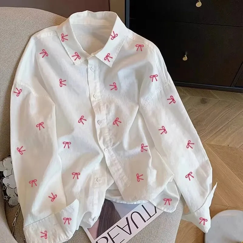 White shirt with red bow patterns on a wooden floor
