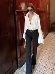 Person wearing a white shirt and black pants in an indoor setting with wooden cabinets.