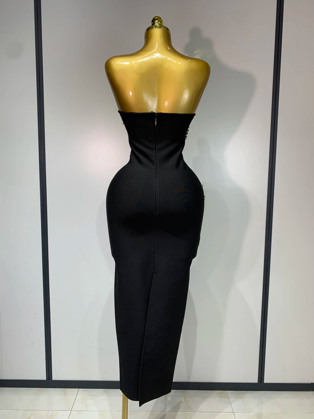 Black evening gown on a mannequin against a plain background