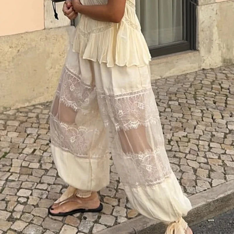 Person wearing a long, light-colored dress with lace details on a stone pavement.