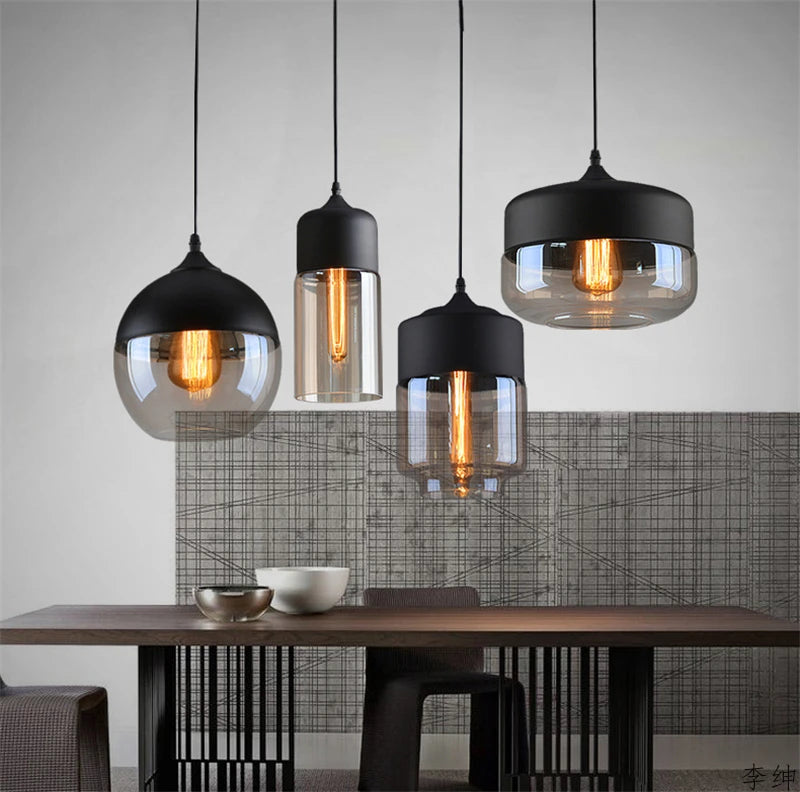 Set of black and clear glass Nordic pendant lamps with LED bulbs hanging above modern dining table
