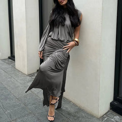 Woman wearing a gray dress standing against a white wall.