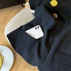 Navy blazer with a white phone in the pocket on a wooden floor.
