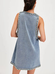 Denim dress with decorative trim on a plain background
