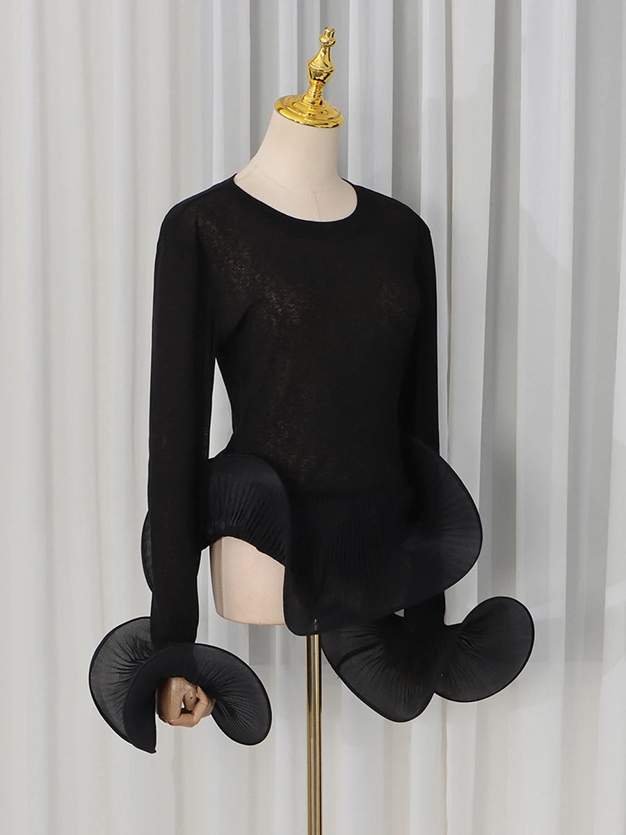 Close-up of the black sheer knit top showcasing sleeve and hem detail