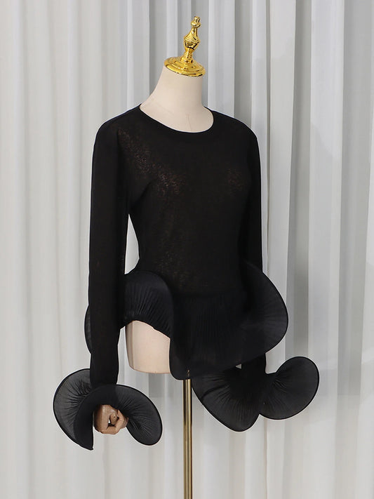 Close-up of the black sheer knit top showcasing sleeve and hem detail