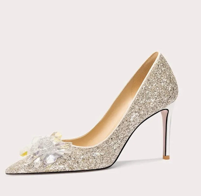 Sparkly high-heeled shoe with decorative flower on a white background