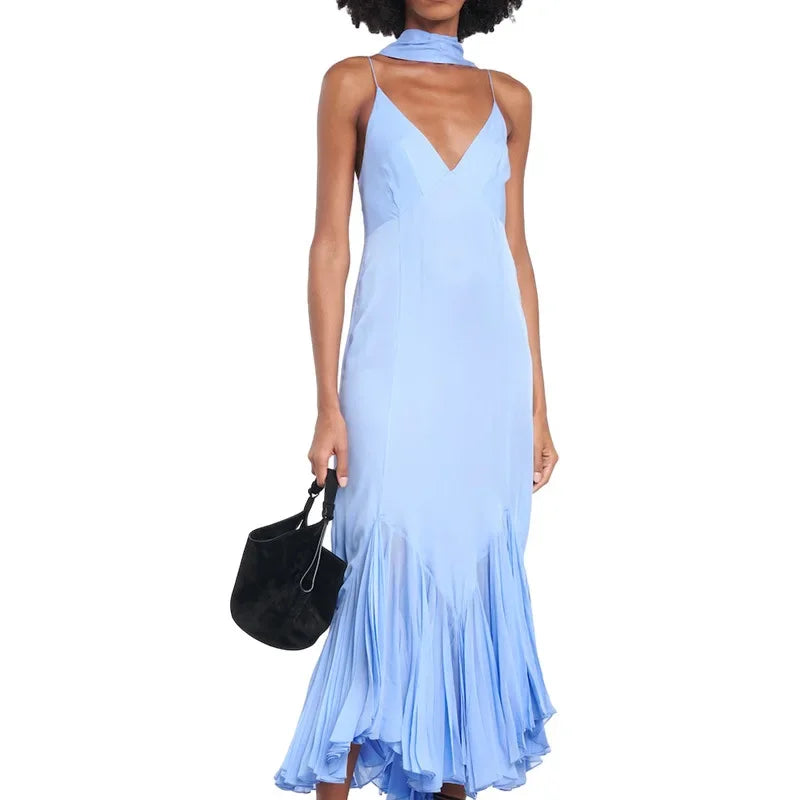 Woman wearing a light blue dress holding a black handbag on a white background