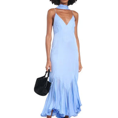 Woman wearing a light blue dress holding a black handbag on a white background