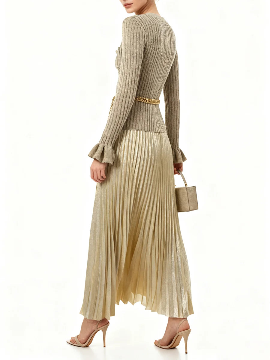 Woman wearing a ribbed sweater and pleated skirt with a gold belt on a white background