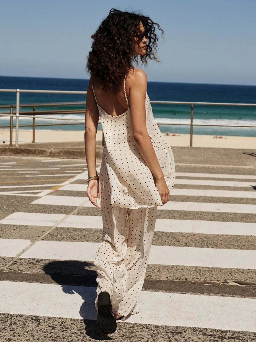 Woman in a polka dot dress standing on a zebra crossing with ocean in the background