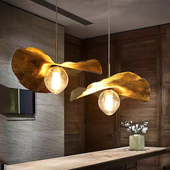 A minimalist brass lotus leaf pendant light casting a warm glow over a modern dining table. B