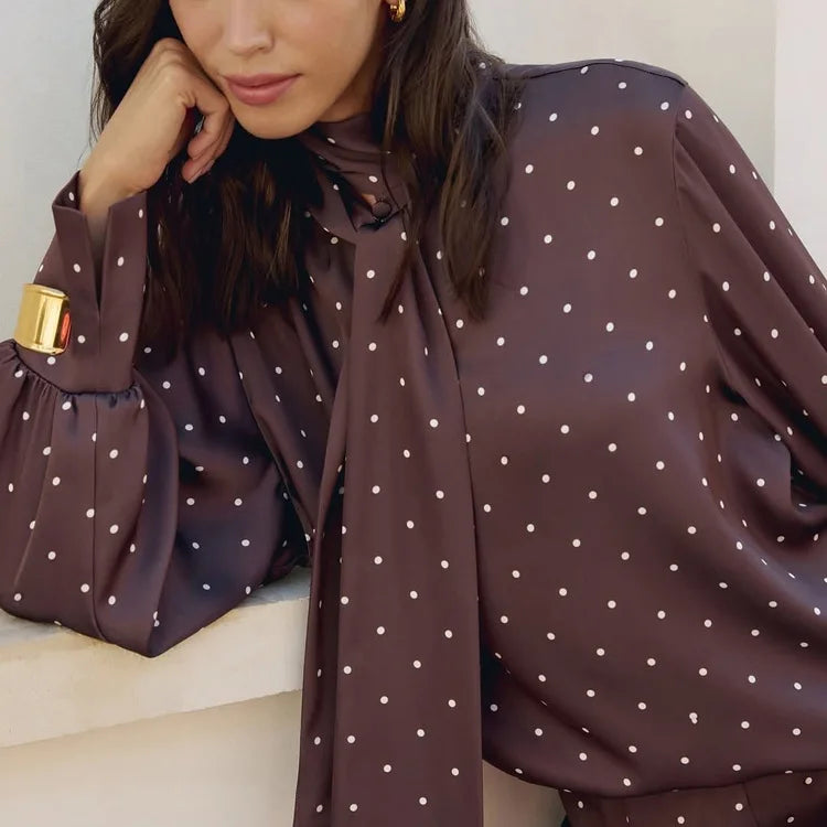 Woman wearing a brown polka dot blouse with a white background
