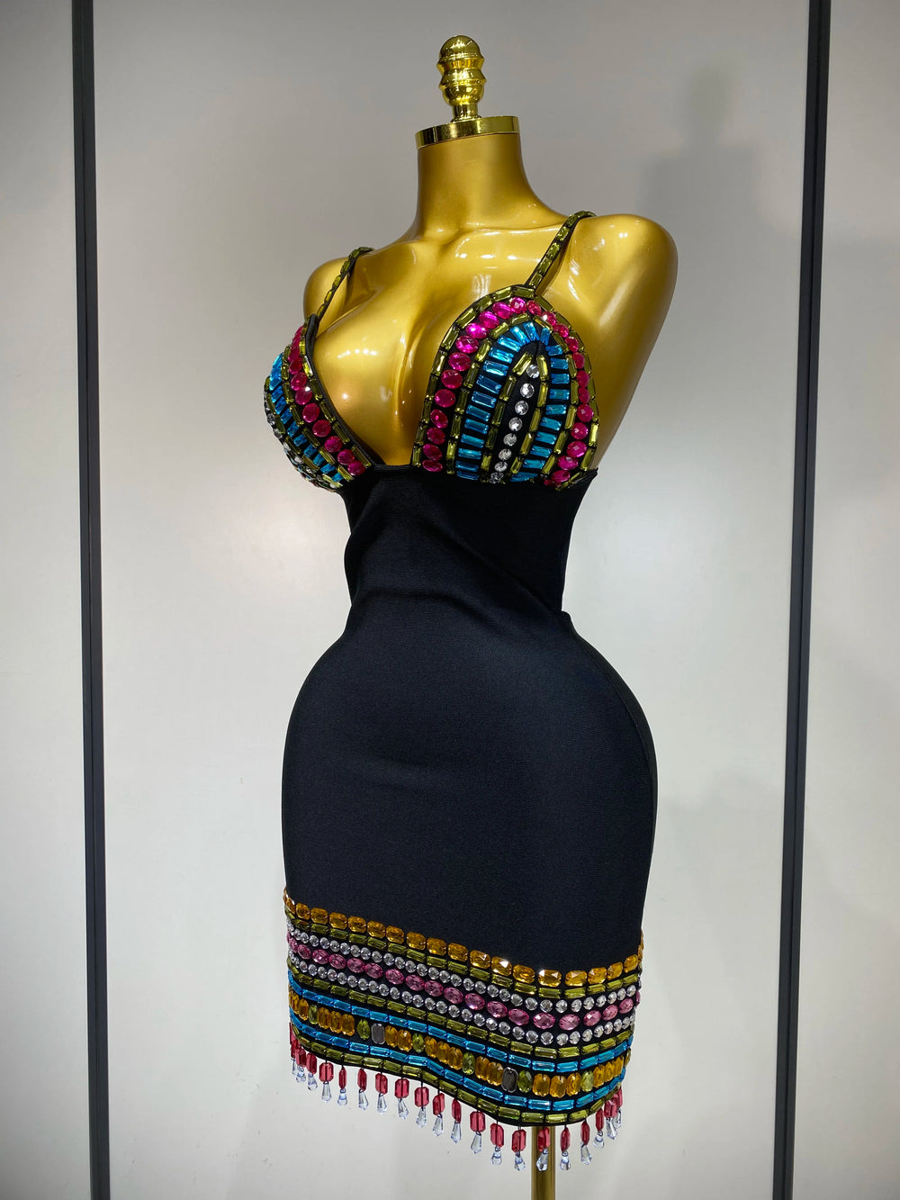 Black dress with colorful beading on a mannequin against a neutral background