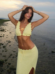 Woman in a yellow crochet outfit standing on a beach.