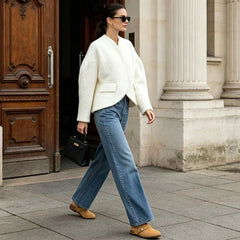 Full outfit view of a woman in a textured white V-neck cropped blazer and jeans.
