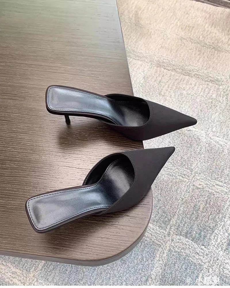 Pair of black high-heeled shoes on a wooden surface.