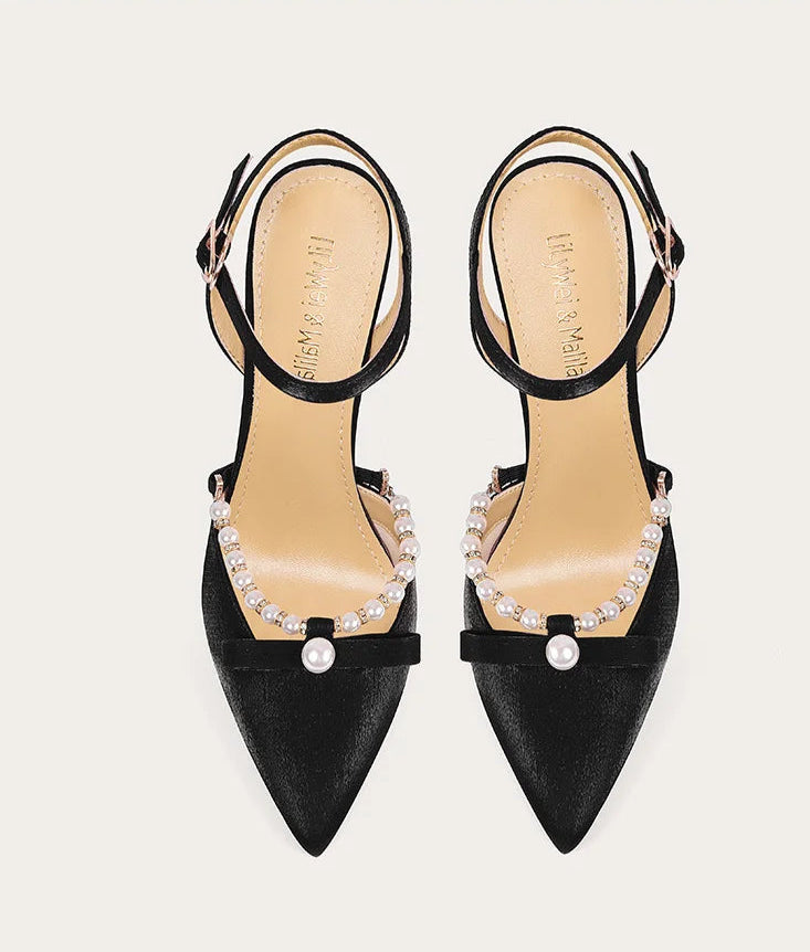 Black high-heeled shoes with embellishments on a white background