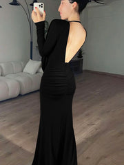 Woman in a black dress taking a mirror selfie in a room with a couch and lamp.
