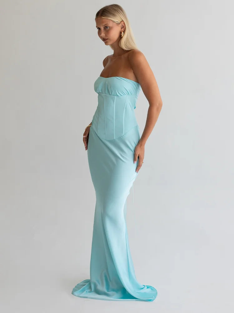 Woman wearing a light blue strapless gown against a plain background
