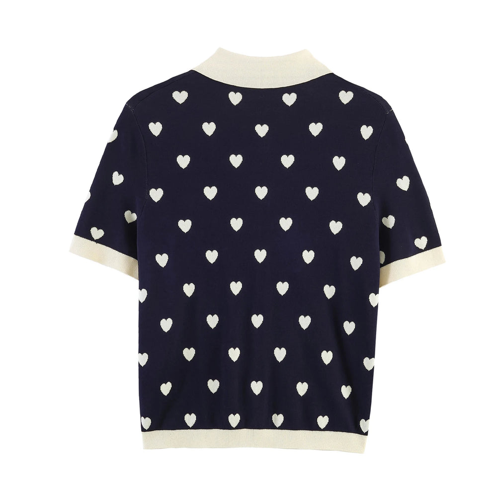 Back view of navy knit polo top with all-over white heart jacquard pattern.