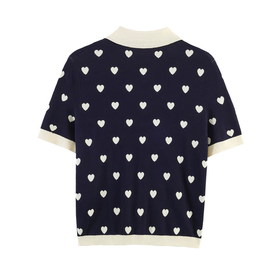 Back view of navy knit polo top with all-over white heart jacquard pattern.