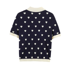 Back view of navy knit polo top with all-over white heart jacquard pattern.