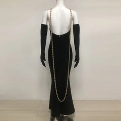 Black evening gown with long train on a mannequin against a plain background