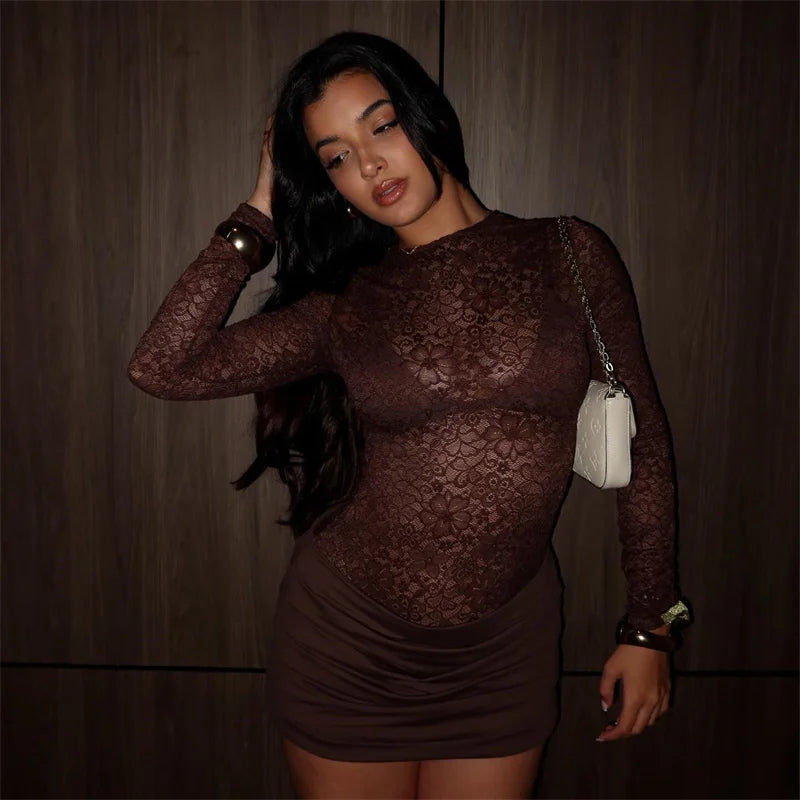 Woman wearing a sheer brown lace dress against a plain background