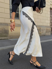 Person wearing a white skirt with black lace trim and black high-heeled shoes on a street.