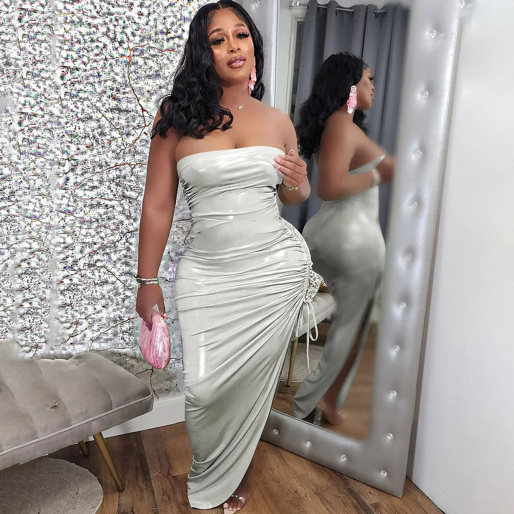 A woman in a strapless  Silver drawstring skirt set is standing in front of a mirror with a decorative wall behind her.