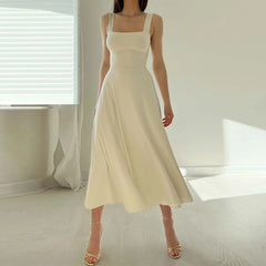 Woman wearing a beige dress in a minimalistic room with white walls and floor.