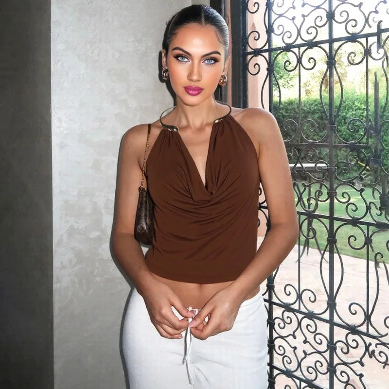 Woman wearing a brown top and white pants standing in front of an iron gate.