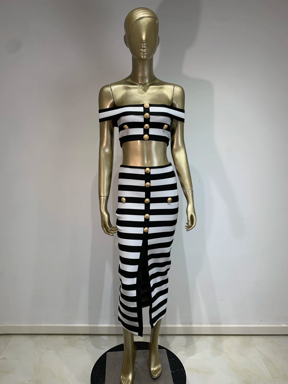 Mannequin wearing a black and white striped outfit with gold buttons against a plain background